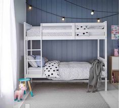 a white bunk bed sitting next to a window with lights hanging from it's sides