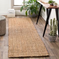 a living room with wooden floors and plants on the wall, along with a rug