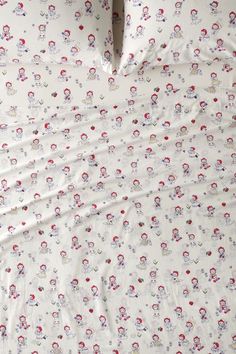 an unmade bed with white sheets and red flowers on the sheet cover, along with two pillow cases