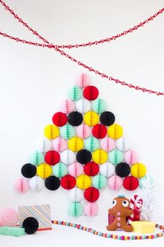 a christmas tree made out of yarn balls and other decorations on a white background with streamers