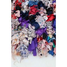 a pile of clothes sitting on top of a white floor next to a wall covered in scarves