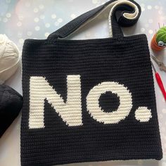 a crocheted bag with the word no written on it next to knitting supplies