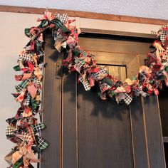 a wreath on the front door is decorated with plaid fabric and bows for holiday decor