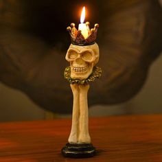 a skull with a crown on it's head sitting next to a lit candle