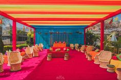 an outdoor wedding venue with bright colors and wicker chairs on red carpeted floor