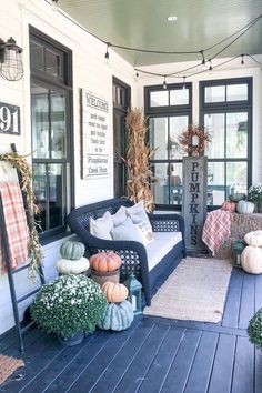 a porch decorated for fall with pumpkins, gourds and other decorations on it