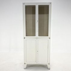 a tall white cabinet with two doors on the front and one door open to reveal an empty shelf