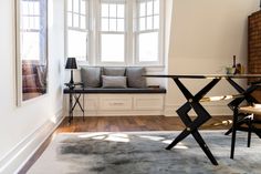 a living room filled with furniture next to a window and a table on top of a hard wood floor