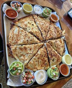 there is a large pancake with many toppings on it and some dipping sauces