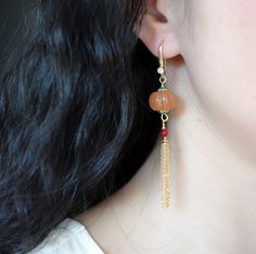 Handmade earrings accented with tassel and quartz pumpkins. Inspired by the jewelry of divine beings depicted in the ancient Chinese paintings of Dunhuang, an oasis town on the Silk Road renowned for its stunning Buddhist art and murals. Style with the Dunhuang necklace for a complete look. Find all the pumpkin designs here. ⚜ Specs Quartz Pumpkin Gemstone Beads 2 pcs❀ Gold Plated Brass Zirconia Ear Wire and Tassels❀ Enamel Caps❀ Length: 3 in. Handpicked private label piece. Traditional Earrings With Natural Stones, Traditional Earrings With Round Natural Stones, Unique Dangle Tassel Jewelry, Tassel Earrings As Festival Gifts, Tassel Earrings For Festivals And Gifts, Festival Tassel Earrings As Gift, Gift Tassel Earrings For Festivals, Handmade Traditional Jade Earrings, Traditional Handmade Jade Earrings