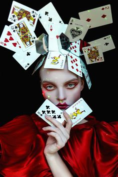 a woman with makeup and playing cards on her head is shown in front of a black background