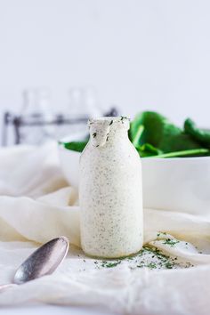 a small white bottle sitting on top of a table next to a bowl and spoon