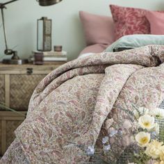 a bed with pink and white flowers in a basket on the floor next to it