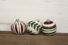 three christmas ornaments sitting on top of a wooden table