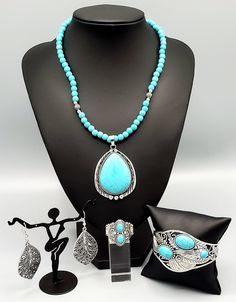 This custom set comes with a necklace and complimentary earrings, upgraded earrings, a cuff bracelet, and a ring with a stretchy back.Necklace - "Evolution": An oversized turquoise stone teardrop is pressed into the center of an ornate silver frame that is studded and stamped in tribal inspired patterns. The rustic pendant glides along an earthy strand of turquoise stone and antiqued silver beads below the collar for a seasonal finish. Features an adjustable clasp closure. Includes one pair of m Back Necklace, Jewelry Fashion Trends, Silver Feather, Silver Filigree, Silver Frame, Turquoise Stone, Silver Band, Matching Earrings, Silver Beads