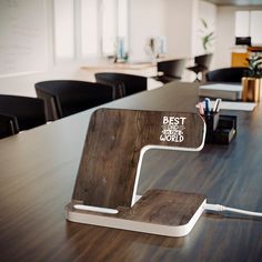 a wooden desk with an electronic device on top of it and office chairs in the background