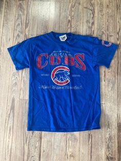 a chicago cubs t - shirt laying on the floor in front of a wooden floor