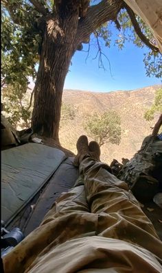 a person laying in a hammock under a tree with their feet on the ground