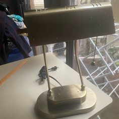 a desk lamp sitting on top of a white table next to a glass window with rain coming through it