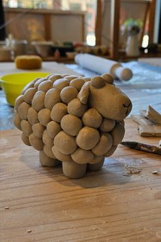 a sheep made out of rocks sitting on top of a wooden table next to construction materials