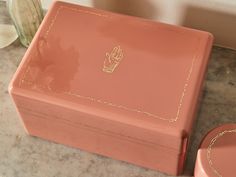 a pink box sitting on top of a counter next to a vase and an object