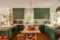 a large kitchen with green cabinets and wooden counter tops, along with an island in the middle