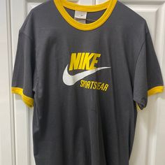 New With Tags Size Large (Seems More Similar To An Xl) Gray T-Shirt With Yellow Trim Design In Collar And Sleeves Vintage Design Single Stitched Gray Moisture-wicking Athleisure T-shirt, Gray Athleisure T-shirt With Letter Print, Gray Sportswear T-shirt For Gym, Gray Sports T-shirt, Gray Short Sleeve Sports Top, Nike Cotton T-shirt In Athletic Heather, Nike Sporty T-shirt With Logo Print, Nike Casual Workout T-shirt, Gray Sporty T-shirt For Sports