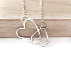 What a perfect delicate necklace. This minimalist necklace is perfect alone or layered with other necklaces. Make the perfect gift to yourself or to a loved one for any occasion. DETAILS - This is a necklace of two small interlinked silver hearts made by 1mm sterling silver wire, shaped, soldered and finished by hand. It has been sanded and polished to give it a shinny look. It is attached on a sterling silver dainty chain with sterling silver spring clasp, the total length of chain includes the Minimalist Adjustable Heart Pendant Necklace, Minimalist Double Heart Charm Necklace With Adjustable Chain, Minimalist Heart Pendant Charm Necklace For Mom, Simple Heart Pendant Necklace For Anniversary, Minimalist Double Heart Jewelry As A Gift For Her, Minimalist Double Heart Jewelry Gift For Her, Minimalist Double Heart Clavicle Necklace, Minimalist Nickel-free Heart Pendant Necklace, Minimalist Handmade Heart Necklace For Everyday