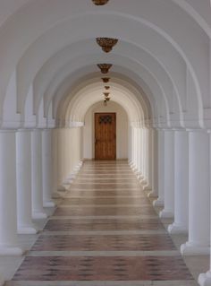 an empty hallway with white columns and wood door