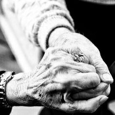 an older woman holding the hand of a younger person on a park bench in black and white