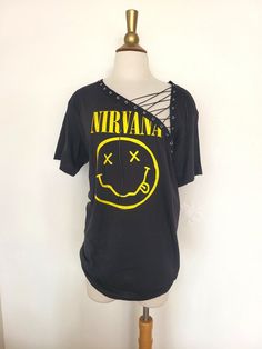 "Nirvana Lace Up Band Top T Shirt - Grunge - Smiley Face Nevermind Each piece is uniquely designed and one of its' kind. Hand stitched edge detailing for superior quality and unique finish. Please note, since this is a handmade item, there may be slight variances with each T.  UNISEX Sizing (women may choose to size down depending on fit preference) Appx. Measurements Laying Flat: S: 17\" across chest Width x 28\" Length M: 19\" across chest Width x 29\" Length L: 21\" across chest Width x 31\" Length ** If you have a custom idea or would like to mix and match a design idea seen in my shop, feel free to contact me anytime **" Vintage Distressed T-shirt For Festivals, Edgy Festival T-shirt With Crew Neck, Edgy Acid Wash T-shirt For Alternative Fashion, Grunge Festival Top With Screen Print, Grunge Screen Print Top For Festival, Festival Grunge Style Top With Screen Print, Band Logo Cotton T-shirt For Festival, Cotton T-shirt With Band Logo For Festival, Edgy Screen Print Tops For Music Festivals