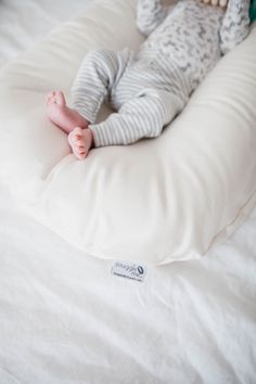 a baby laying on top of a white pillow