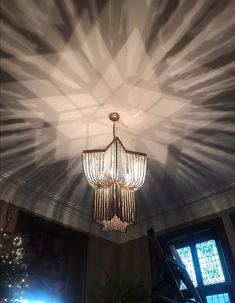 a chandelier hanging from the ceiling in a room with lights shining on it