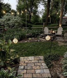 two lawn chairs sitting on top of a lush green field next to a fire pit