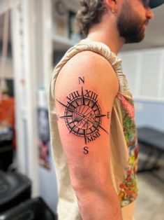 a man with a compass tattoo on his arm