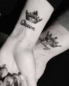 two people holding hands with tattoos on their wrists that say queen and princess crowns