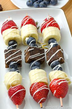 several desserts are arranged on a plate with strawberries and blueberries