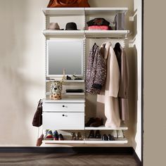 a white closet with clothes and shoes on the shelves next to a wall mounted mirror