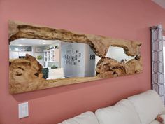 a mirror that is on the wall above a couch in a room with pink walls