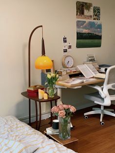 a room with a bed, desk and chair in it next to a clock on the wall