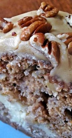 a close up of a piece of cake on a plate with icing and nuts