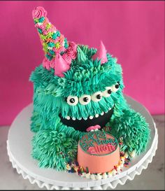 there is a cake that looks like a monster on top of a table with pink and green decorations