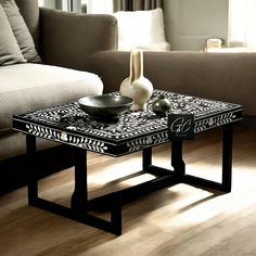 a black and white table sitting on top of a wooden floor next to a couch