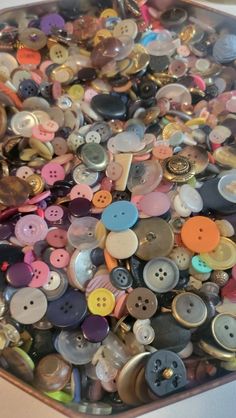 there are many different buttons in the tray on the table and one is full of them