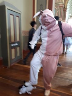 a person in a pink and white outfit is dancing on a wooden floor with other people