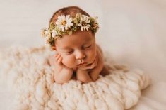 a baby laying on top of a blanket wearing a flower crown