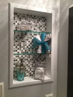 a bathroom shelf with towels and soaps on it in front of a tiled wall