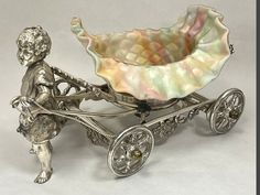 a silver figurine with a baby in a buggy on it's side