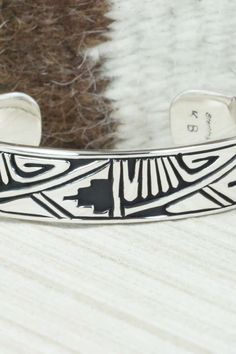 This sterling silver and bracelet was made by Navajo silversmith Kerry Begay. The inside is signed KB and stamped sterling.Size: 5" (will fit up to a 6" wrist)Gap: 1"Width: 1/2"Free shipping on all orders! We ship with USPS and always include tracking. All orders ship within a day of payment.Returns are accepted up to 30 days after you receive your order. Just send us a message. Our shop offers cash back or store credit. The item must be returned in new condition. Stamped Sterling Silver Bangle Bracelet, Southwestern Sterling Silver Inlay Bracelet Gift, Stamped Sterling Silver Bangle, Sterling Silver Etched Bangle Bracelet, Etched Sterling Silver Bangle, Artisan Sterling Silver Cuff Bracelet For Collectors, Artisan Sterling Silver Bracelet With Inlay, Artisan Sterling Silver Bracelet With Oxidized Finish, Unique Adjustable Etched Sterling Silver Bracelet