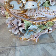 an ornately decorated table with flowers on it's sides and gold trimmings